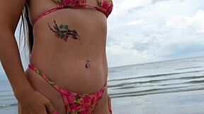 Petite brunette walks the beach in a sexy bikini enjoying public fun