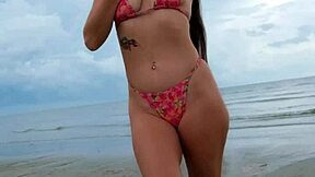 Petite brunette walks the beach in a sexy bikini enjoying public fun